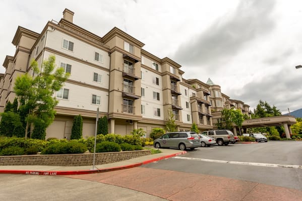 Exterior of University House Issaquah showing the main entrance and parking area.