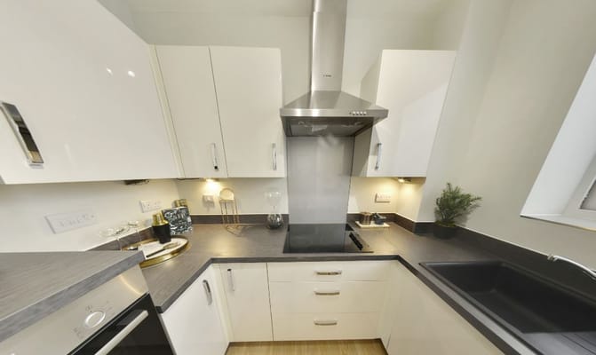 A modern kitchen with sleek white cabinets and black countertop.