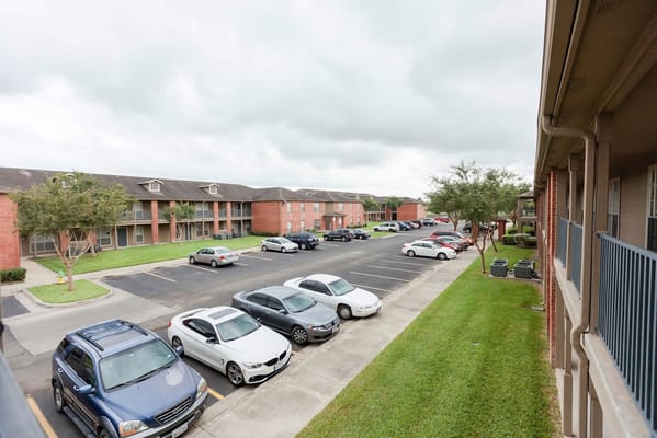 A view of the parking lot at Valley Resaca Palms Apartments with several cars and apartment buildings.