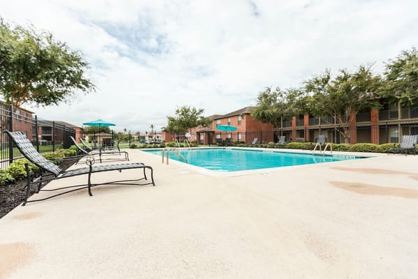 Swimming pool surrounded by lounge chairs and greenery
