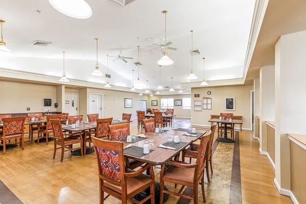 Dining area with tables and chairs set for a meal at Victoria Place Senior Living.