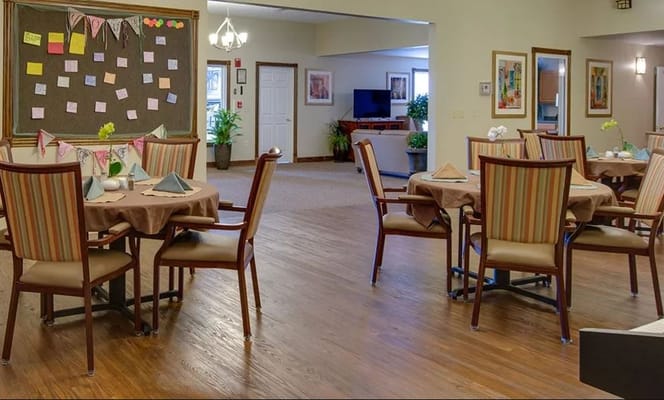 Brightly colored dining area with tables set for meals and a bulletin board in the background.
