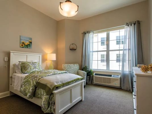 A well-decorated bedroom with a bed, armchair, and window