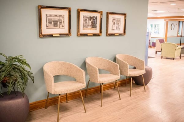 Three modern chairs next to framed artwork on a wall