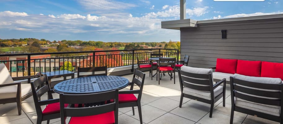Rooftop lounge area with seating and tables, overlooking scenic views.