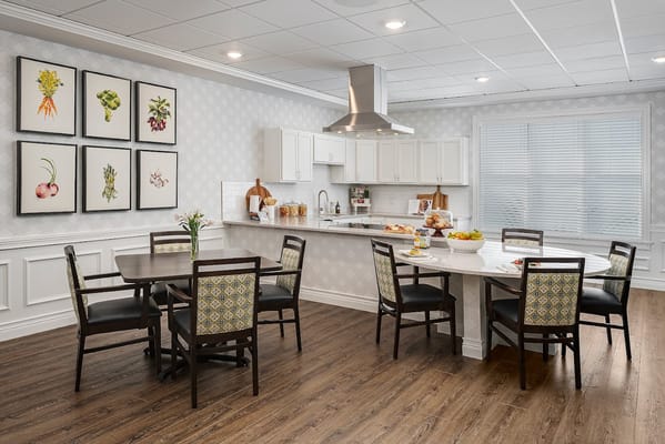 Modern kitchen and dining area with wooden flooring and floral artwork.