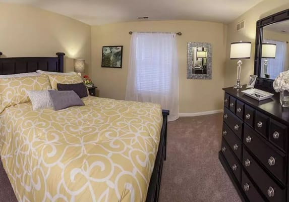 Cozy bedroom featuring a yellow patterned comforter and dark wood furnishings.