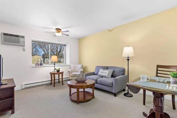 Living room furnished with a sofa, armchair, and dining table.