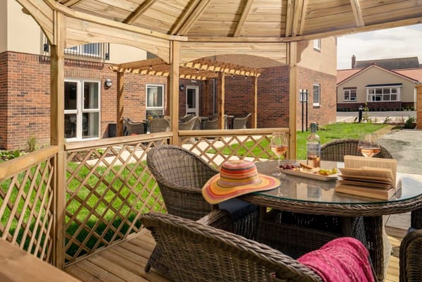 Cozy outdoor seating area with a table, wine, and a sunhat at Waveney Place.