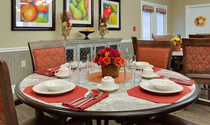 Brightly set dining table with floral centerpiece and colorful artwork on the walls.