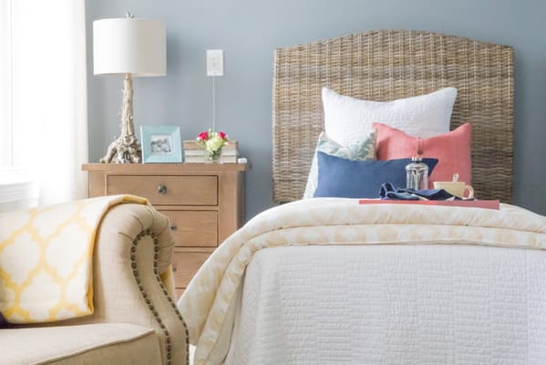 A cozy bedroom featuring a bed with decorative pillows and a wooden nightstand.