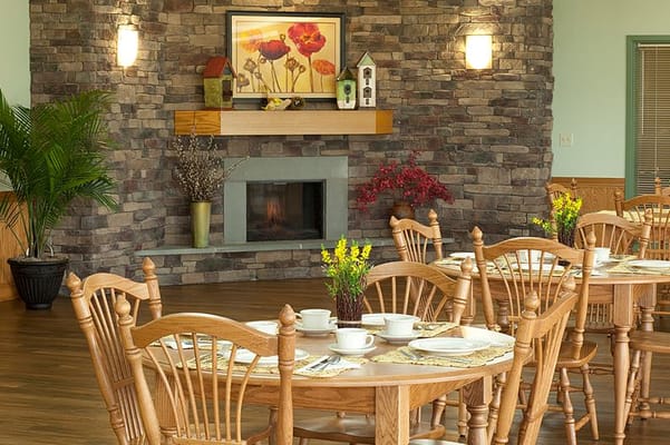Cozy dining area with wooden tables and chairs, decorated with flowers.