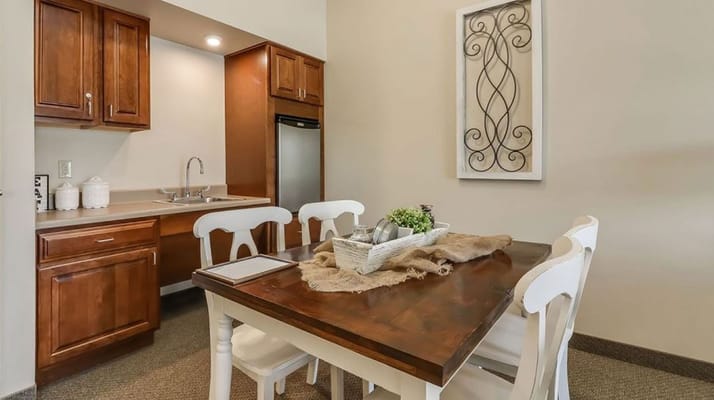 A wooden dining table with white chairs in a kitchenette.