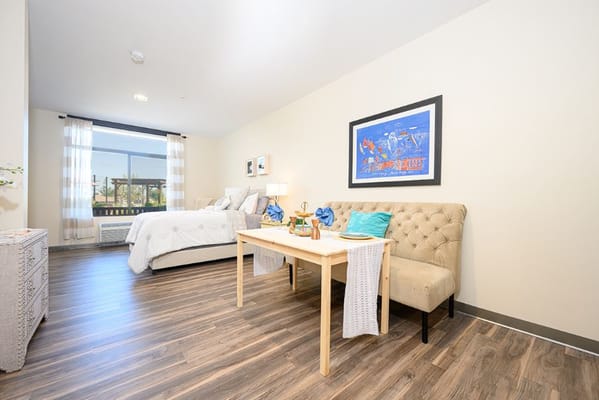 A well-furnished resident room with a small seating area