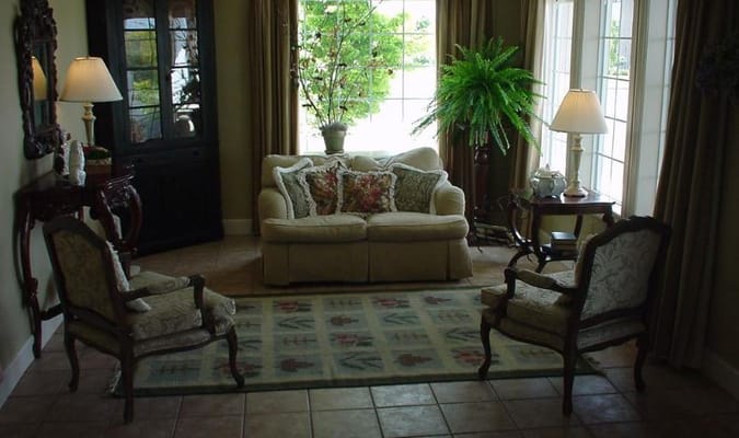 A cozy living room with a sofa, armchairs, and large windows