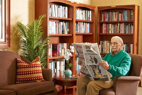 Resident reading a newspaper in a cozy common area