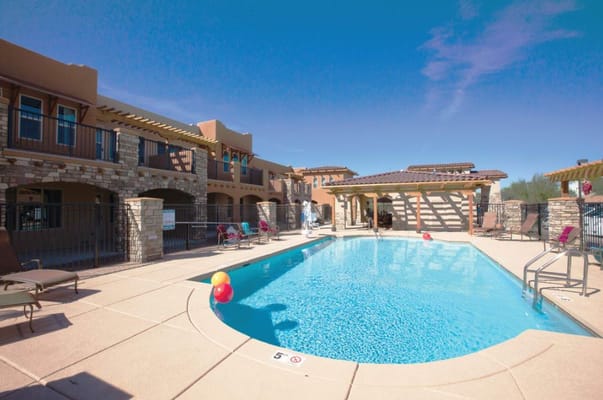 Swimming pool surrounded by lounge chairs and a shaded patio.