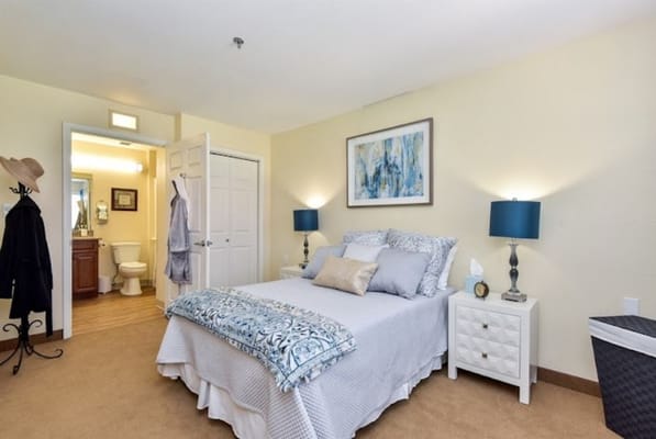 Clean and inviting bedroom with a bed, lamps, and a bathroom door