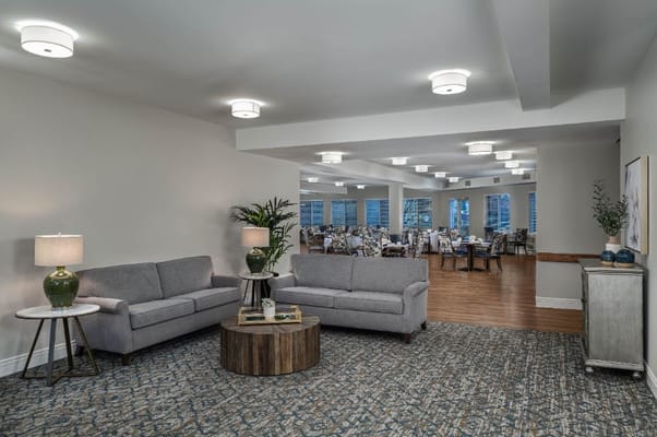 A modern living room with gray sofas and a dining area in the background.