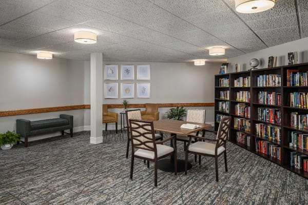 A cozy common area with a table, chairs, and bookshelf in Hart Park Square.