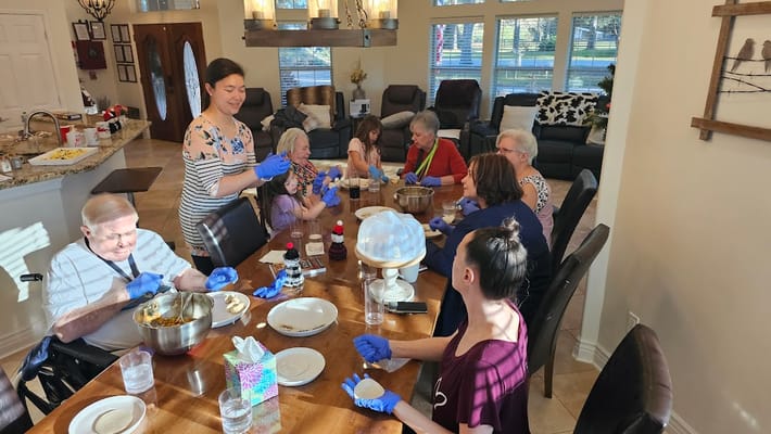 Residents and staff engaged in an activity around a dining table