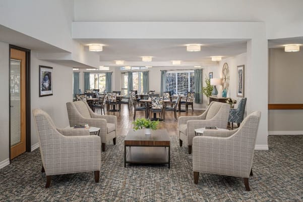 Comfortable seating area with chairs and a coffee table in a senior living facility lounge.