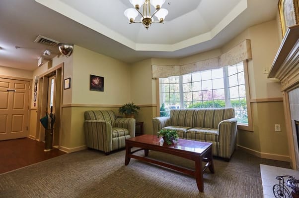 Lounge area with a striped couch, armchair, and coffee table in a senior living facility
