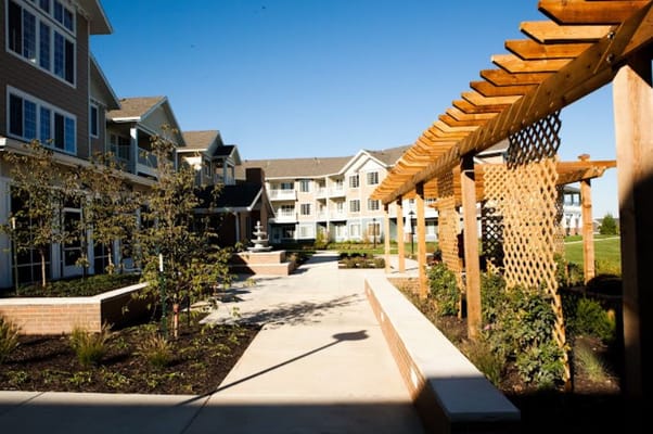 A landscaped courtyard with a wooden pergola and greenery at Meadowlark Estates