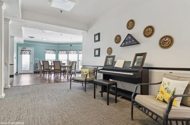 Cozy lounge area with seating, a piano, and decorative wall art.