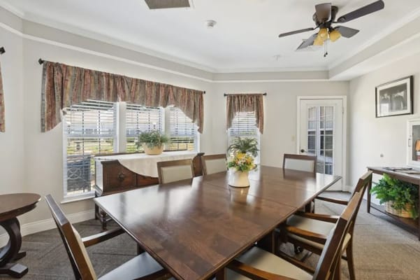 A spacious dining room with a large wooden table and bright window views.