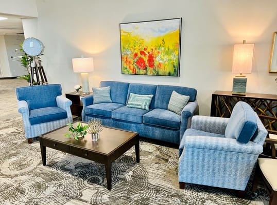 Cozy lounge area with blue sofas, a coffee table, and colorful artwork.
