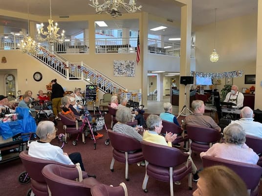 Seniors clapping and enjoying a live music performance in the common area.