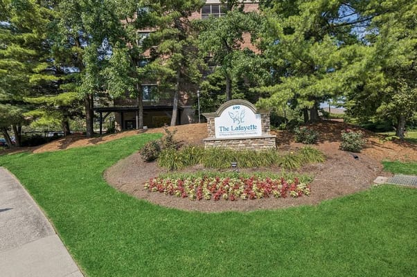 The Lafayette senior living facility entrance sign surrounded by greenery and flowers.