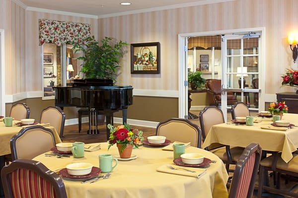 Elegant dining area with tables set for a meal and a piano