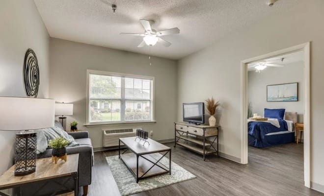 Cozy living room featuring a sofa, coffee table, and a view of a bedroom