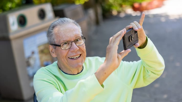 Senior man taking a photo outdoors on a sunny day
