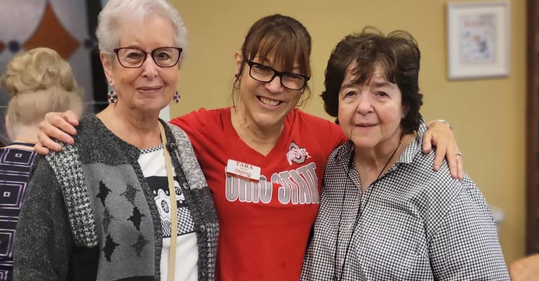 Three women smiling together in a communal setting