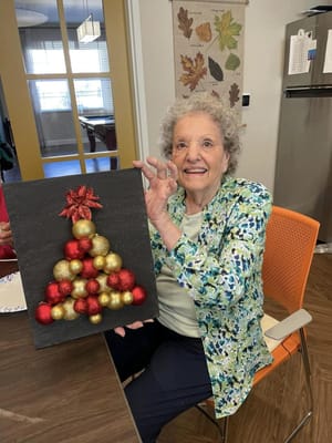 Resident showcasing a craft in a decorated common room