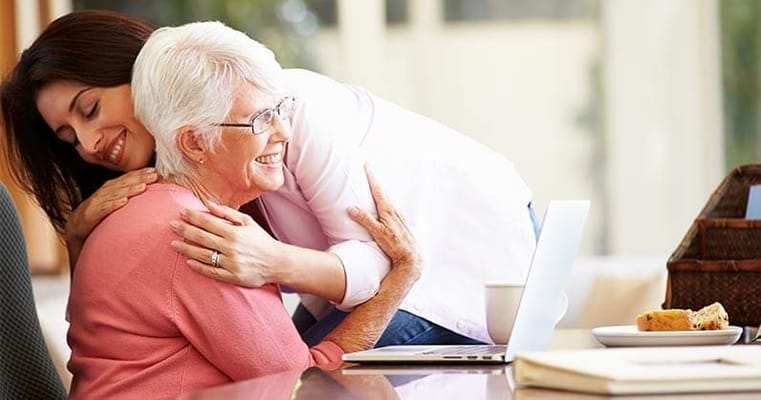 Caregiver embracing a smiling resident at a table
