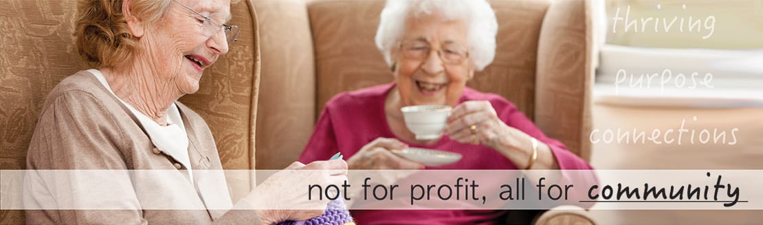 Two smiling residents enjoying tea and knitting