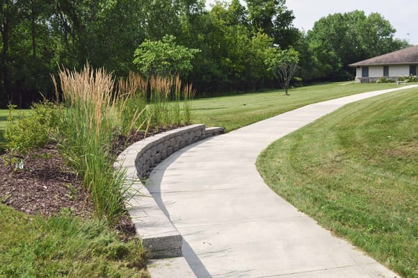 Curved walkway lined with grass and shrubs
