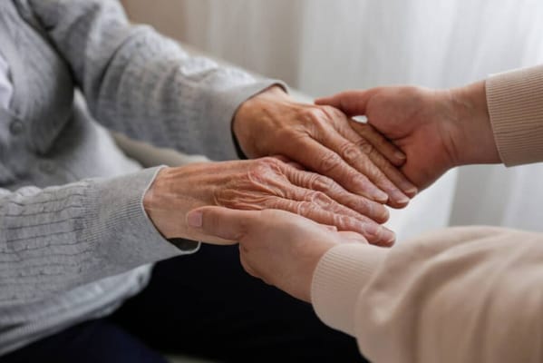 Hands of a resident and caregiver reaching out