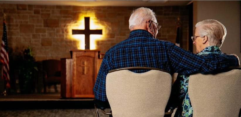 Senior couple sitting in front of a chapel