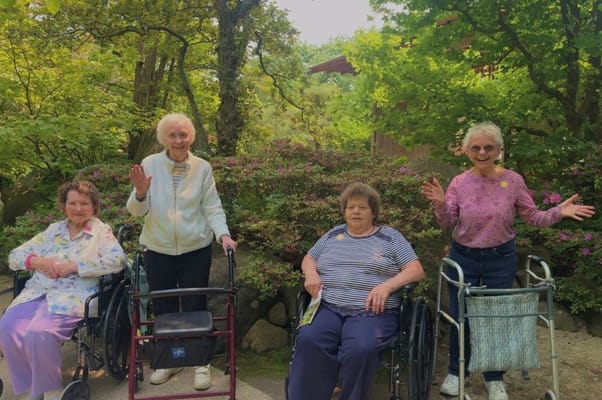 Four residents in wheelchairs smiling outdoors
