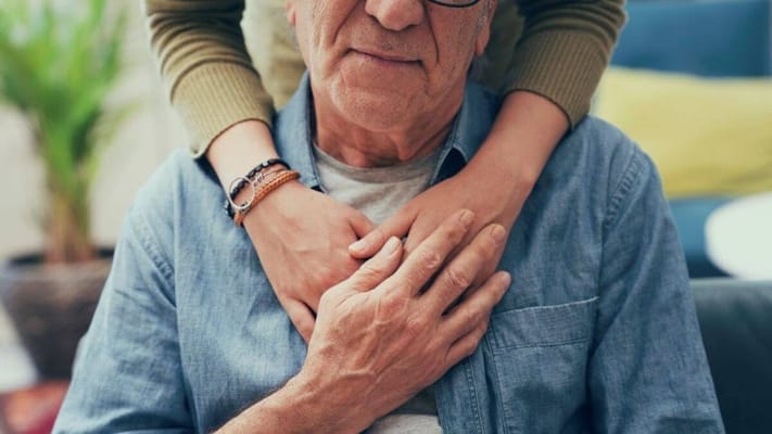 An elderly man with a younger individual embracing him