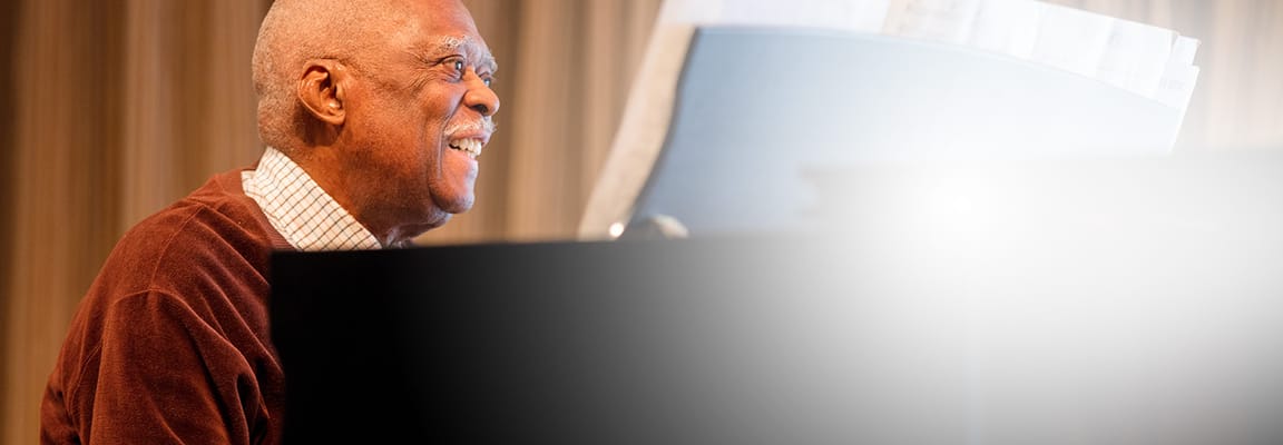 An elderly man joyfully playing the piano