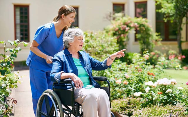 Caregiver assisting a woman in a wheelchair in a garden