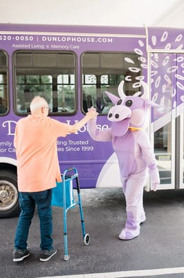 Resident interacting with a costumed character by the bus