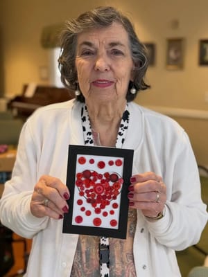 A resident holding a framed artwork made from buttons