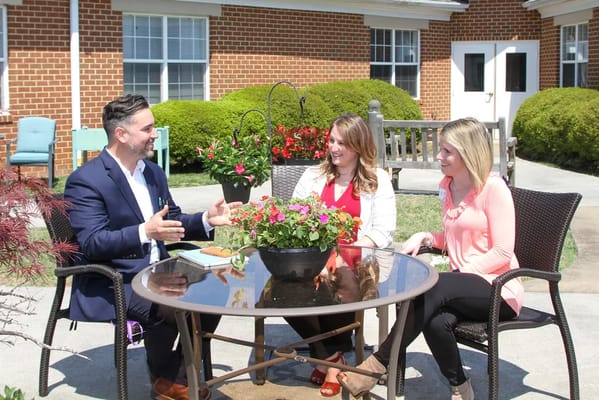 Three people seated at a table in an outdoor area